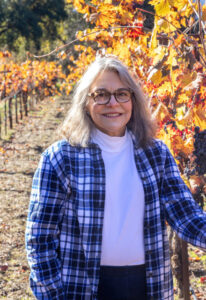 Lori Sarkisian Taylor standing in vineyard.