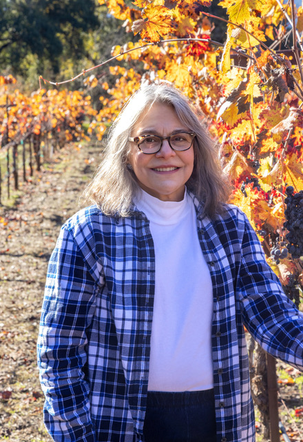 Lori Sarkisian Taylor standing in vineyard.