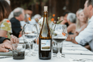 DCVA Summer Social at Bella Bella Vineyards & Wine Caves - photo shows a Bella Vineyards bottle on a table during an outdoor event.
